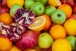 Fruit background, apples, opened pomegranate, orange, Delicious winter fruits on a stall, variety of healthy ripe fruits 