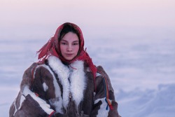 Young girl, in the national winter clothes of the northern inhabitants of the tundra, the Arctic circle, frosty haze