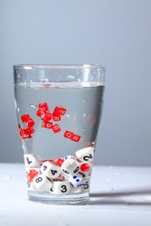 cubes with letters and numbers are submerged in water, letters and numbers are drowned in a glass of water