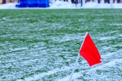 red flag on the corner of a soccer field in winter. football field empty in winter