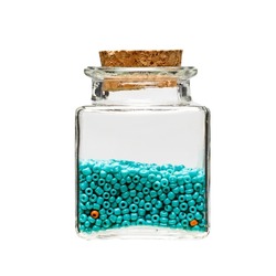 turquoise beads in a glass jar on a white background. storage of decorative items