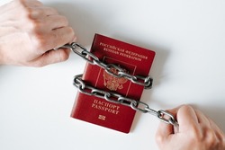 Canceled international biometric passport of citizen of Russian Federation. Close-up of male hands chaining passport, top view. Sanctions, ban, culture of canceling Russia concept.