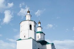 Close-up religious architecture of Middle Ages. Ancient white church, old monastery facade against blue sky outdoors.
