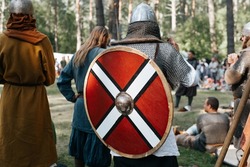 Knights of war preparing for battle in forest outdoors. Back view of viking in helmet, chain mail with round shield on back. Middle Ages concept.
