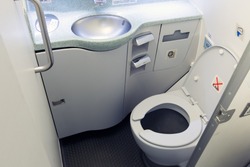 Airplane lavatory. Toilet seat and wash basin close-up.
