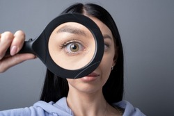 Woman looking through a magnifying glass, searching for a Finding concept . Funny humor image 