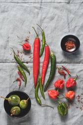 Assortment of fresh and  dried hot peppers on natural linseed blue background: cayenne,  Charleston Hot, Carribean red habanero  on  the dark background