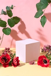 Summer floral background, style of showcase for cosmetics product, display on yellow and pink background with red flowers. Pink cube platform with flowers, light and shadows, front view 