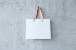 Mock-up of blank craft package, mockup of white paper shopping bag with handles on the concrete background.