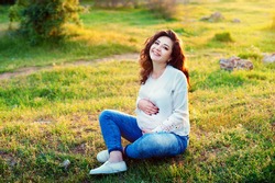 pregnancy, motherhood and happiness concept - happy pregnant woman touching her belly
