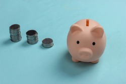 Piggy bank and stack of coins on blue background, saving money, wealth and financial for investment