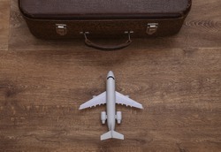 Travel concept. Air plane and old travel suitcase on wooden floor. Top view