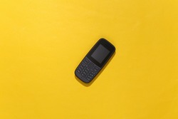 Push-button telephone on yellow background. Top view
