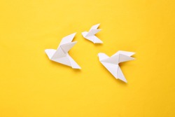 Origami paper doves on a yellow background. Peace symbol