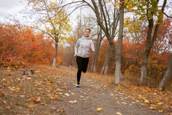 Woman runner in autumn park or forest. Healthy lifestyle, jogging