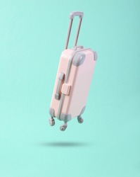 Mini travel luggage soaring on a blue background. Minimalism travel concept 