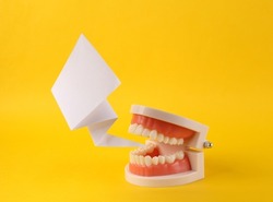 Talking model of human jaw with dialog blank comic cloud on yellow background