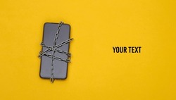 Smartphone wrapped in a steel chain on yellow background. Safety of personal information. Top view