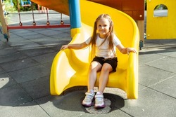 Little girl is sliding down the slide in the playground