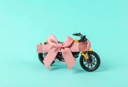 New toy motorbike wrapped with gift ribbon on blue background