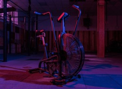 Airbike, professional exercise bike with aerodynamic loading system in pink-blue neon light in a modern health class. Cross training
