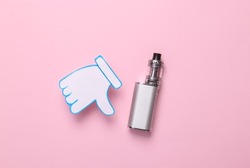 Harm of smoking electronic vaping devices concept. Thumbs down icon with vaping device on pink background