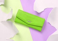Leather green purse on two tone background with torn paper. Concept art. Pastel color trend. Top view
