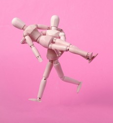 Wooden Puppet run in arms with puppet on pink background