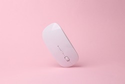 Modern wireless pc mouse flying in antigravity on pink background with shadow. Levitation object in the air. Computer techologies concept. Creative minimal layout