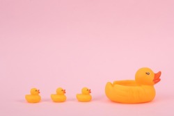 Rubber mother duck with ducklings on a pink background