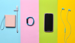 Power bank, smart watches, headphones, smartphone lined on a colorful background. Top View