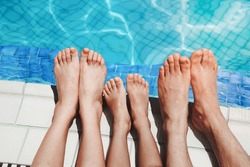 Close up of three people's legs by the pool side