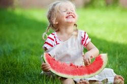 Funny baby eating watermelon outdoors in the park. Baby, baby, healthy food