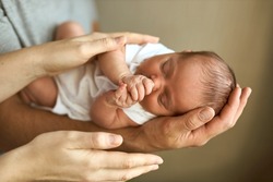 Parents hands holding newborn baby head. Motherhood, fatherhood or parenthood and fathers day concept. Modern parenthood. Comfort and safety sleep. Human insurance. Family miracle.