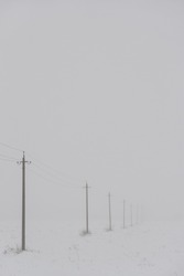 Snow fog in a field with high-voltage poles extending into the impenetrable distance