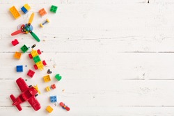 Top view on multicolor toy bricks on white wooden background. Children toys on the table.