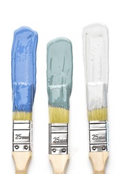 Three paintbrushes dipped in shade of blue, green and Grey. one line has been painted in each colour on a white surface. Compared side by side