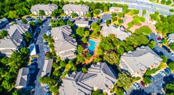 Curved modern swimming pool and bright lush green trees surrounding cozy new development suburb apartment complex townhomes - aerial drone view - Round Rock , Texas , USA