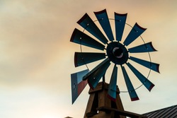 Texas windmill at golden hour sunset glowing in the farm glow