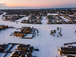 snow covered landscape above Austin Texas after winter storm Uri during morning sunrise over suburb homes 