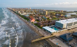 drone view high above the Beach Vacation Travel Destination of South Padre Island , Texas , USA long pier and many condos and buildings across the island