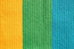Eye-pleasing crochet pattern in three different soft colors yarn: yellow, green and blue cotton thread, symmetrical background created by the continuous half double stitches as handicraft inspiration