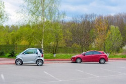 Photo of car parking with small white and red cars near the park
