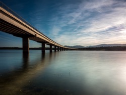 Long bridge over a lake with still water at evening, blue hour (calm scene, serenity concept)