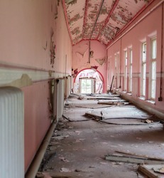 Abandoned corridor with decaying walls inside Whittingham Mental Asylum, the largest abandoned hospital in Europe