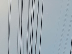 Background of electrical cables against a clear sky.