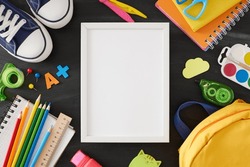 Embrace fresh start of the school year. Top view shot of pair of shoes, educational supplies, rucksack, A+ badge on blackboard background with empty frame for advert or text