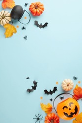 Capturing the enigmatic magic of Halloween. Top view vertical photo of pumpkin basket, witch brooms, pots, pumpkins, autumn leaves, halloween decorations on light blue background with ad space