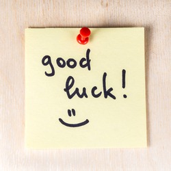 Good luck note on paper post it pinned to a wooden board