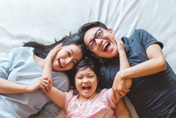 Happy Asian family laying on bed in bedroom with happy and smile, top view